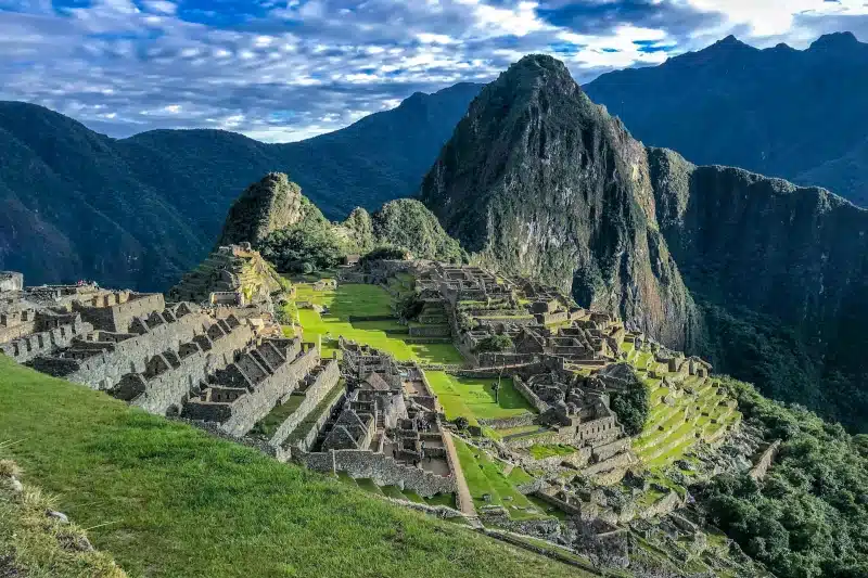 Sunlit view of Machu Picchu with Huayna Picchu rising behind the ruins, marking the final arrival of the Classic Inca Trail through the Sun Gate