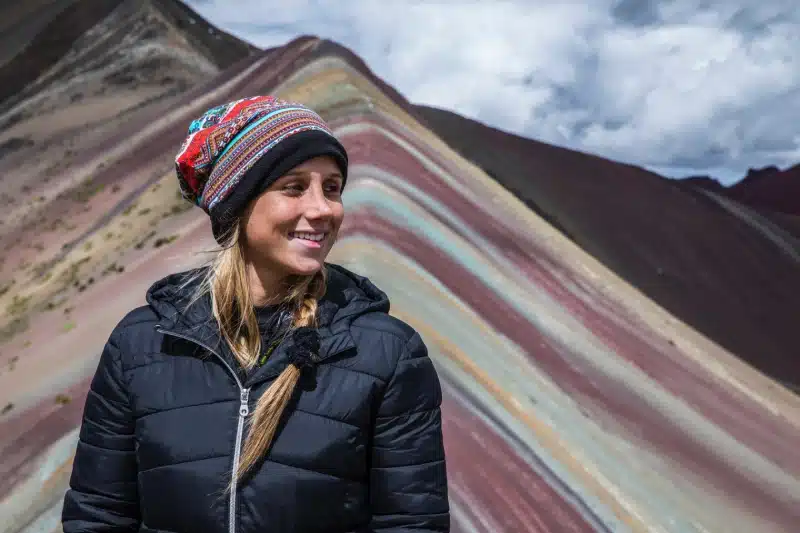 Traveler standing before Rainbow Mountain during the Ausangate Trek, showcasing Peru’s mineral-rich landscapes and high-altitude beauty