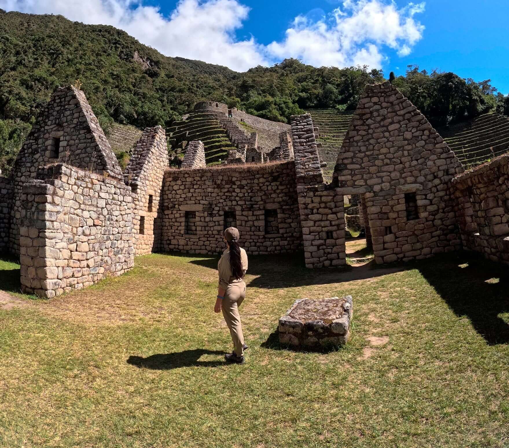 Traveler standing before ancient Inca stone ruins with terraced hills and sunlight – Best of Cusco Tour – Peru Hikers