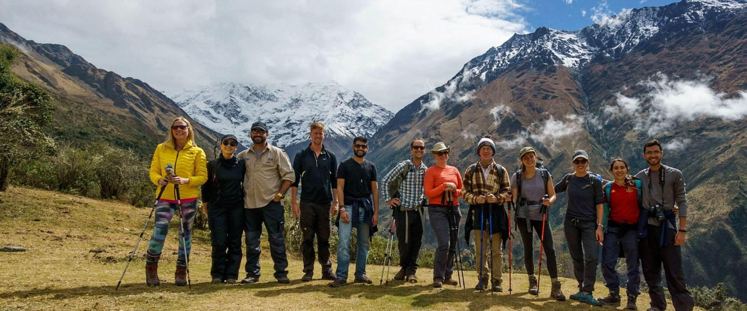 Happy group of hikers on the Salkantay Trek with stunning Andean mountains - Peru Hikers