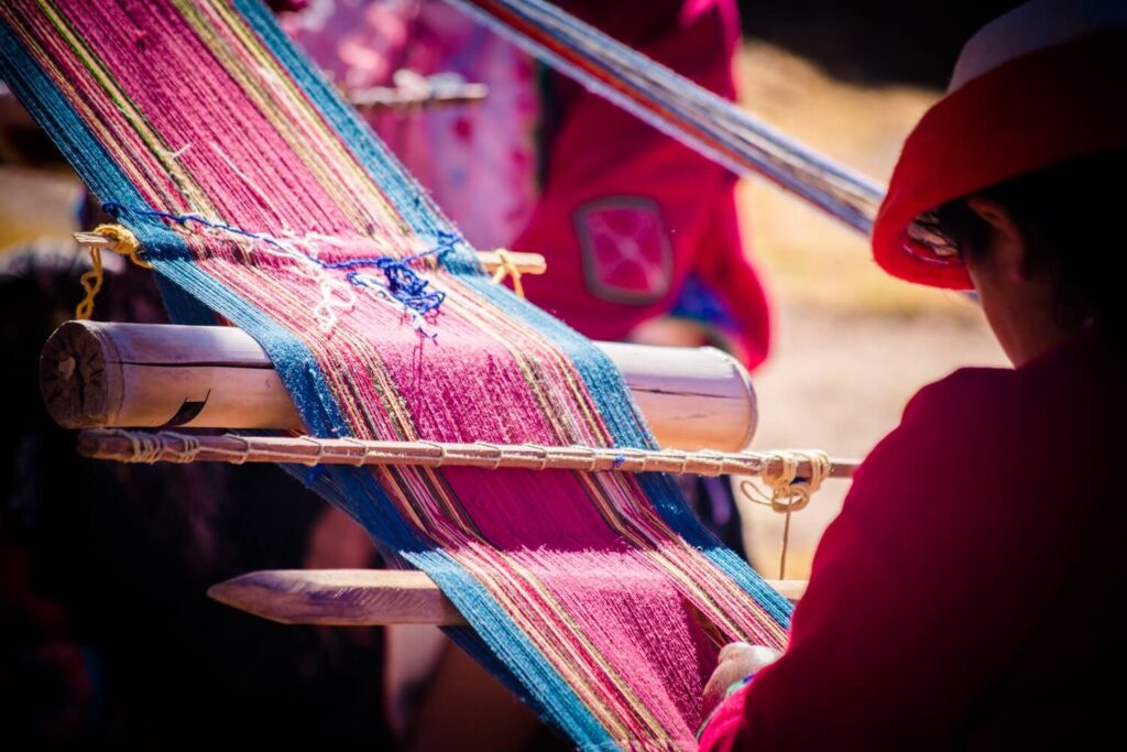 Andean woman weaving vibrant textiles with backstrap loom – Sacred Valley cultural experience – Peru Hikers