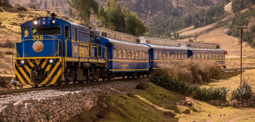 Blue and yellow Expedition train crossing scenic Andean landscape – Peru Hikers