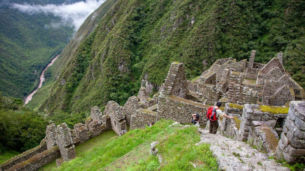 Trekkers exploring the Wiñay Wayna ruins on the Inca Trail. This site is key when considering Inca Trail duration options, known as Peru's most famous trek, with the Urubamba valley below.