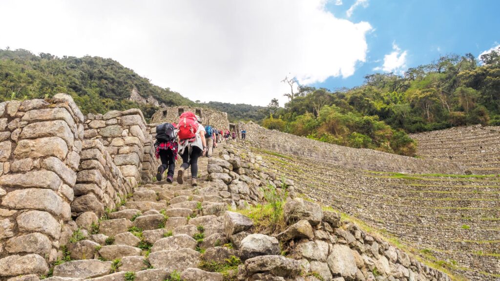 Group of hikers ascending Inca stone stairs surrounded by lush vegetation, capturing the spirit of the Short Inca Trail for Beginners – Peru Hikers