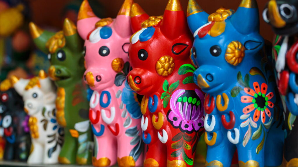 Row of colorful painted Toritos de Pucará, traditional ceramic figures and one of the best souvenirs from Cusco - Peru Hikers