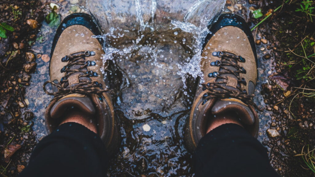 A hiker stands in a puddle, demonstrating why the best hiking boots for the Inca trail must be waterproof. - Peru Hikers